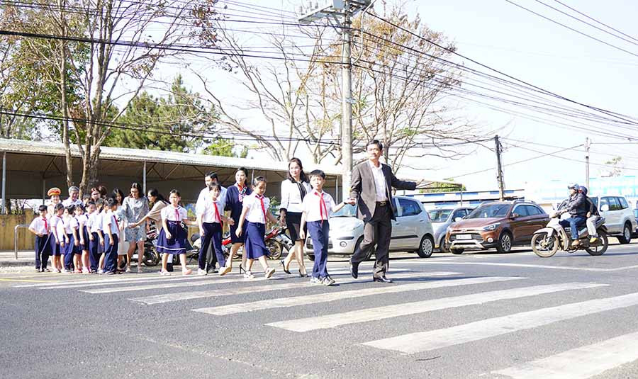Thành viên Ban An toàn Giao thông tỉnh, đại diện dự án “Giảm tốc độ-Trường học an toàn” hướng dẫn học sinh qua đường an toàn. Ảnh: L.H  Thành viên Ban An toàn Giao thông tỉnh, đại diện dự án “Giảm tốc độ-Trường học an toàn” hướng dẫn học sinh qua đường an toàn. Ảnh: L.H