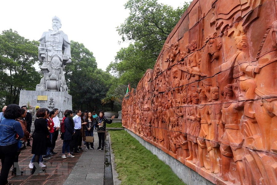 Du khách tham quan bức phù điêu ghi lại chiến công lịch sử được làm bằng đất nung cạnh Tượng đài Hưng Đạo Vương Trần Quốc Tuấn trong quần thể Đền Cao An Phụ.