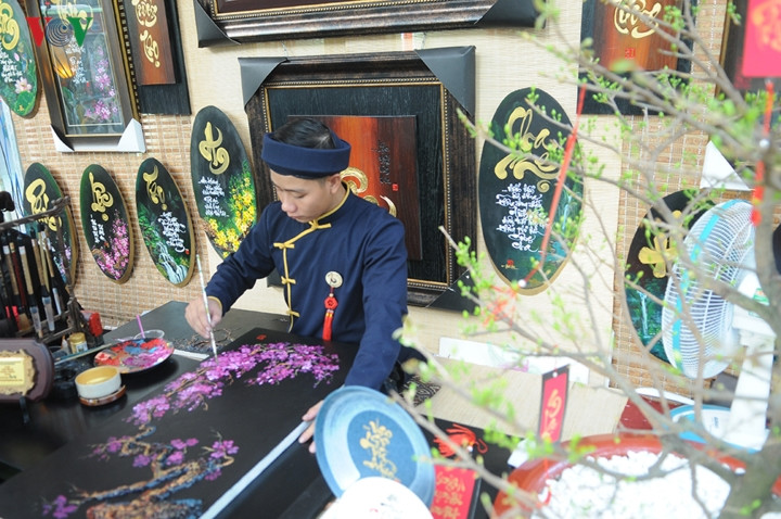 Ông Đồ trẻ say sưa vẽ tranh bán cho khách.