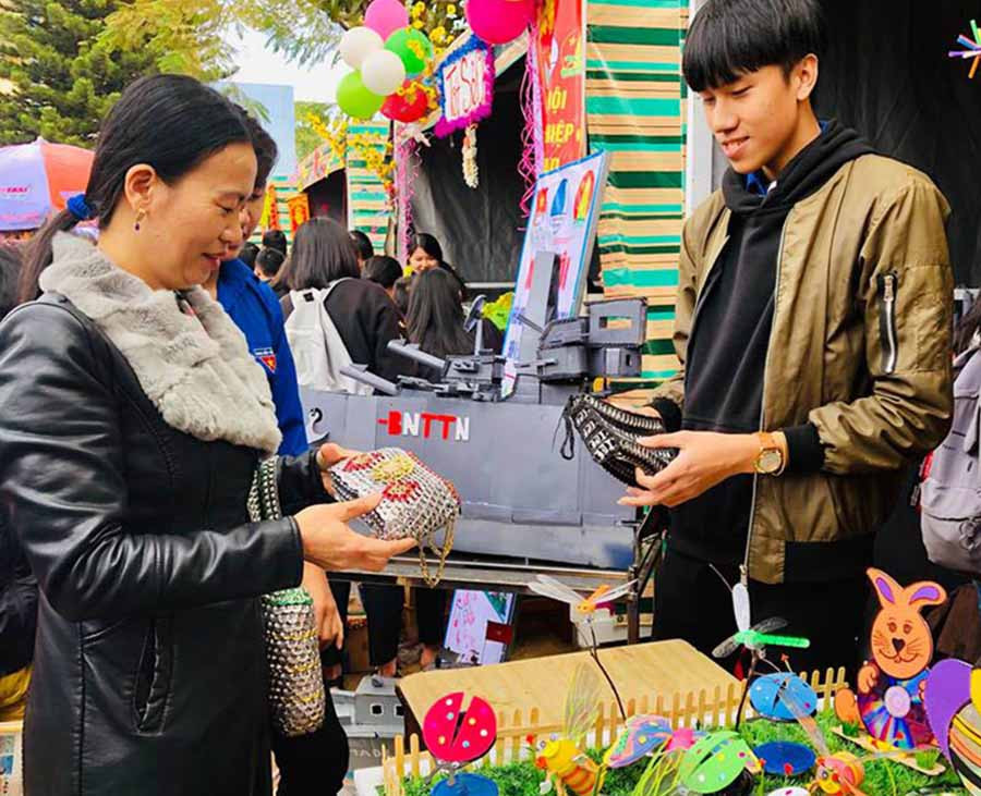 Một khách hàng quan tâm đến sản phẩm túi xách làm từ lon bia được bày bán tại ngày hội. Ảnh: T.B