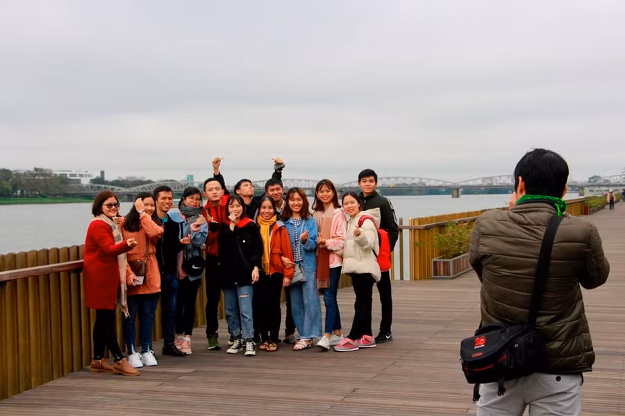  Nhóm bạn trẻ từ nơi khác đến Huế hào hứng chụp ảnh kỷ niệm ở cầu đi bộ lót sàn gỗ lim.