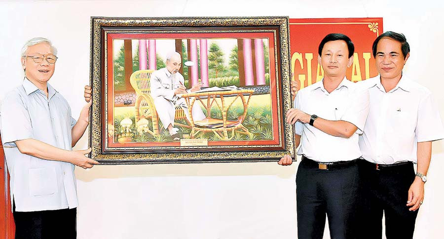 Tổng Bí thư Nguyễn Phú Trọng (bìa trái) tặng tranh “Bác Hồ ngồi làm việc trong vườn hoa” cho tỉnh (tháng 4-2017). Ảnh: Đ.T
