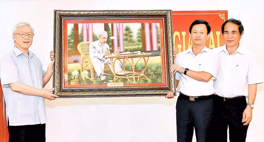 Tổng Bí thư Nguyễn Phú Trọng (bìa trái) tặng tranh “Bác Hồ ngồi làm việc trong vườn hoa” cho tỉnh (tháng 4-2017). Ảnh: Đ.T