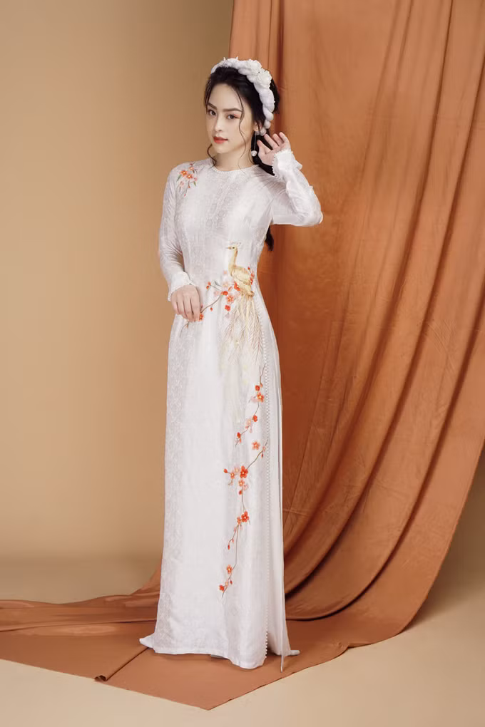 Áo dài được điểm họa tiết cành đào xuân và chim công thể hiện không khí tươi vui, rộn rã, phù hợp với đám cưới diễn ra vào mùa đầu tiên trong năm.