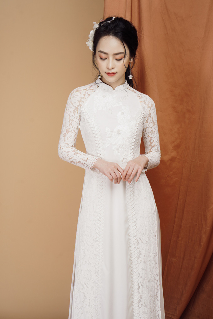Mẫu áo dài ren được thêu hoa trắng trên ngực tô thêm nét đẹp tinh khôi, e ấp của nàng dâu mới. Dải dây leo chạy dọc thân giúp kéo dài chiều cao cơ thể của người mặc. Mẫu áo dài ren được thêu hoa trắng trên ngực tô thêm nét đẹp tinh khôi, e ấp của nàng dâu mới. Dải dây leo chạy dọc thân giúp kéo dài chiều cao cơ thể của người mặc.