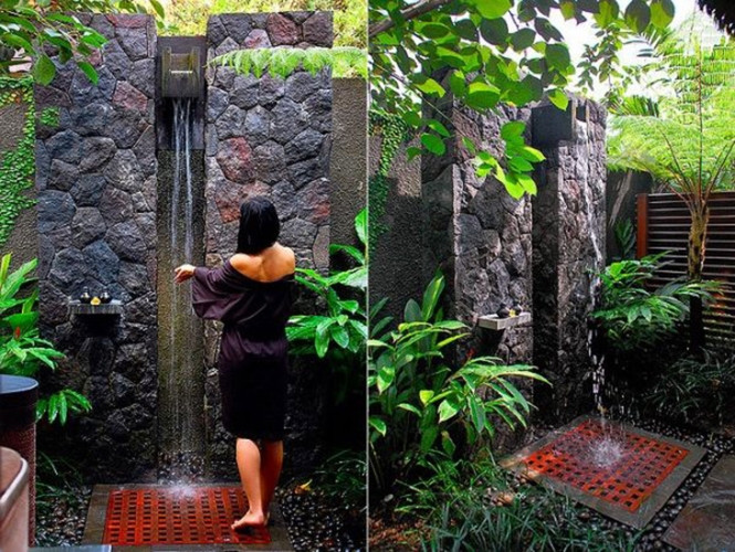 Phòng tắm ngoài trời ở khu nghỉ dưỡng Kayumanis, thị trấn Ubud, Indonesia với thác nước nhỏ bằng gỗ nằm giữa hai phiến đá. Xung quanh thác nước là cây cỏ, dương xỉ và sàn lát sỏi đá.  Phòng tắm ngoài trời ở khu nghỉ dưỡng Kayumanis, thị trấn Ubud, Indonesia với thác nước nhỏ bằng gỗ nằm giữa hai phiến đá. Xung quanh thác nước là cây cỏ, dương xỉ và sàn lát sỏi đá.