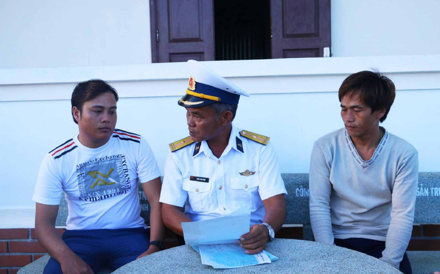  Ngư dân Đinh Văn Lực (trái) được Thiếu tá Trần Văn Bỉnh (giữa) hướng dẫn, tuyên truyền và phát tờ rơi khi ra khơi bám biển. Ảnh: Quang Tấn