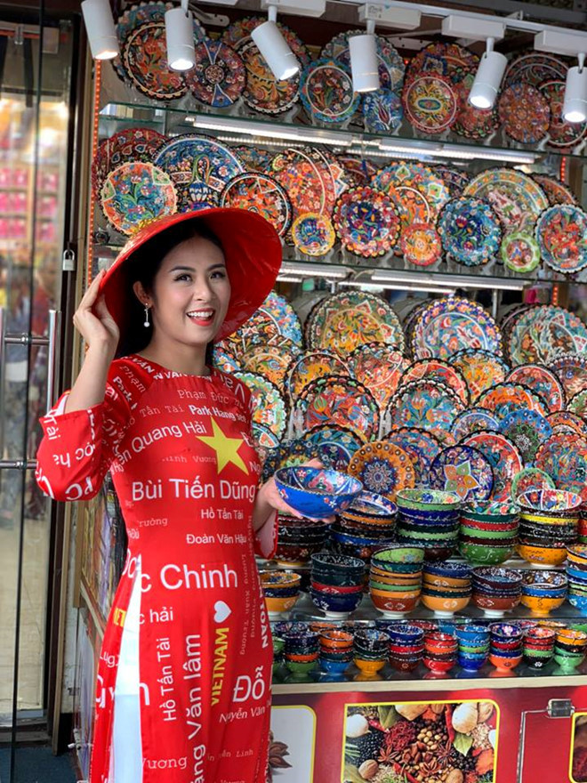 Cô gây chú ý khi mặc áo dài đỏ, in tên các cầu thủ tại Dubai. Ảnh: NVCC. Cô gây chú ý khi mặc áo dài đỏ, in tên các cầu thủ tại Dubai. Ảnh: NVCC.