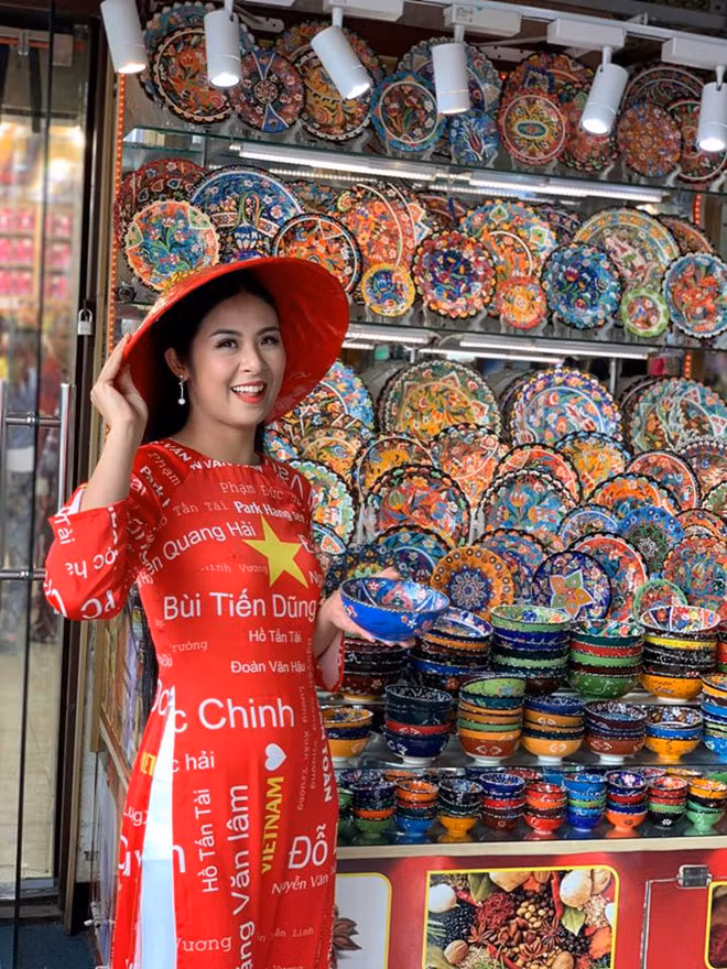 Cô gây chú ý khi mặc áo dài đỏ, in tên các cầu thủ tại Dubai. Ảnh: NVCC. Cô gây chú ý khi mặc áo dài đỏ, in tên các cầu thủ tại Dubai. Ảnh: NVCC.