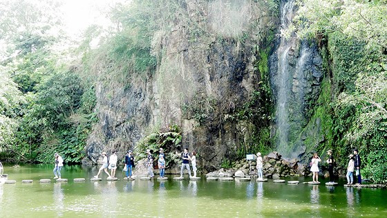 Du khách tận hưởng cảm giác mát lạnh bên dưới dòng thác trong khu du lịch