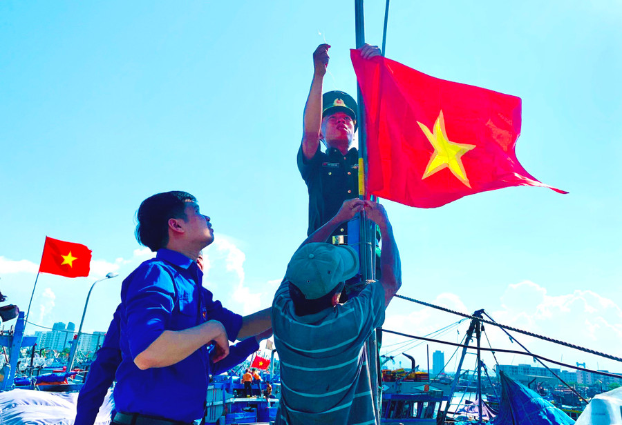 Trung úy Phan Hoàng Hiệp treo cờ Tổ quốc lên tàu cá chuẩn bị vươn khơi, bám ngư trường Hoàng Sa - ẢNH: S.X