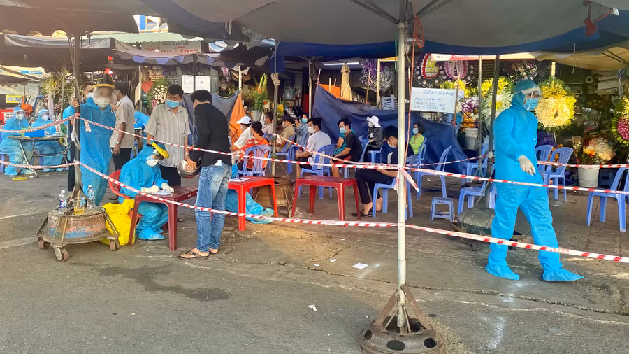 Người dân chờ lấy mẫu xét nghiệm được xếp ngồi giãn cách theo quy định. ẢNH: HÂN HỒ