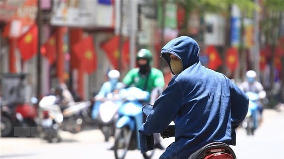 Dưới cái nóng thiêu đốt, người dân tham gia giao thông phải trang bị áo mũ chống nắng kín mít để tránh nắng. (Ảnh: Hoàng Hiếu/TTXVN)