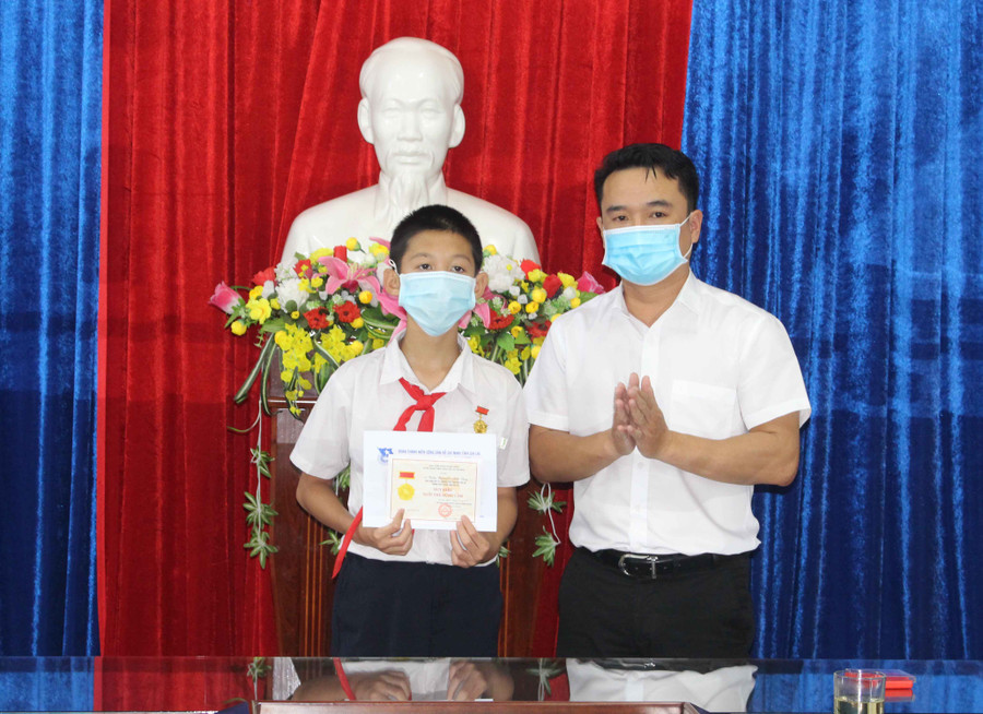 Anh Đỗ Duy Nam (bìa phải)-Phó Bí thư Tỉnh Đoàn trao tặng huy hiệu “Tuổi trẻ dũng cảm” cho em Trần Nguyễn Anh Duy. Ảnh Phan Lài.