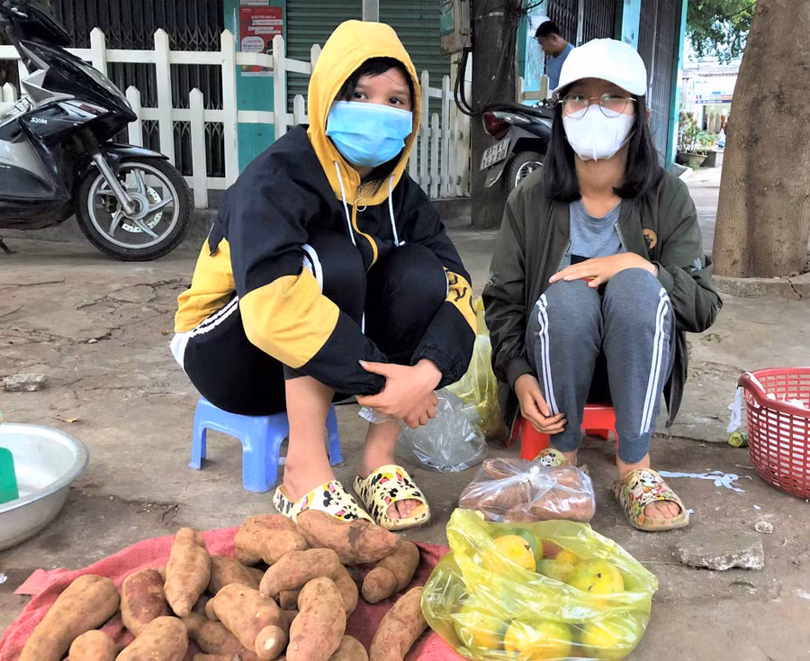 Em Nguyễn Thị Bích Vân (bìa phải) và Nguyễn Thị Bảo Nhi bán củ quả ở một góc vỉa hè chợ Yên Thế. Ảnh: Hà Tây