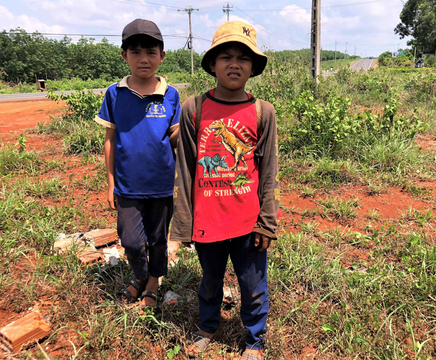 Em KPă Luân (bìa phải) và KPă Khích (bìa trái) trên đường đi nhặt phân bò. Ảnh. Hà Tây