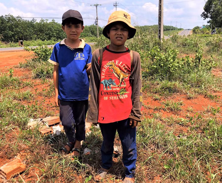 Em KPă Luân (bìa phải) và KPă Khích (bìa trái) trên đường đi nhặt phân bò. Ảnh. Hà Tây