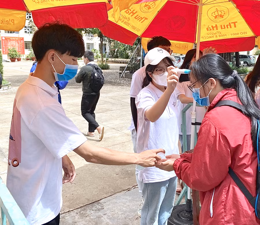 Tất cả thí sinh được kiểm tra thân nhiệt, rửa tay sát khuẩn và bắt buộc đeo khẩu trang trước khi bước vào khu vực thi. Ảnh: Mộc Trà