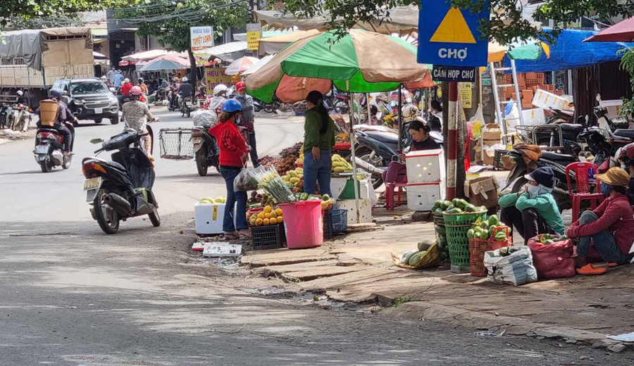 Mặc dù có biển cấm họp chợ nhưng người dân vẫn bày bán tràn ra đường. Ảnh: Hà Phương