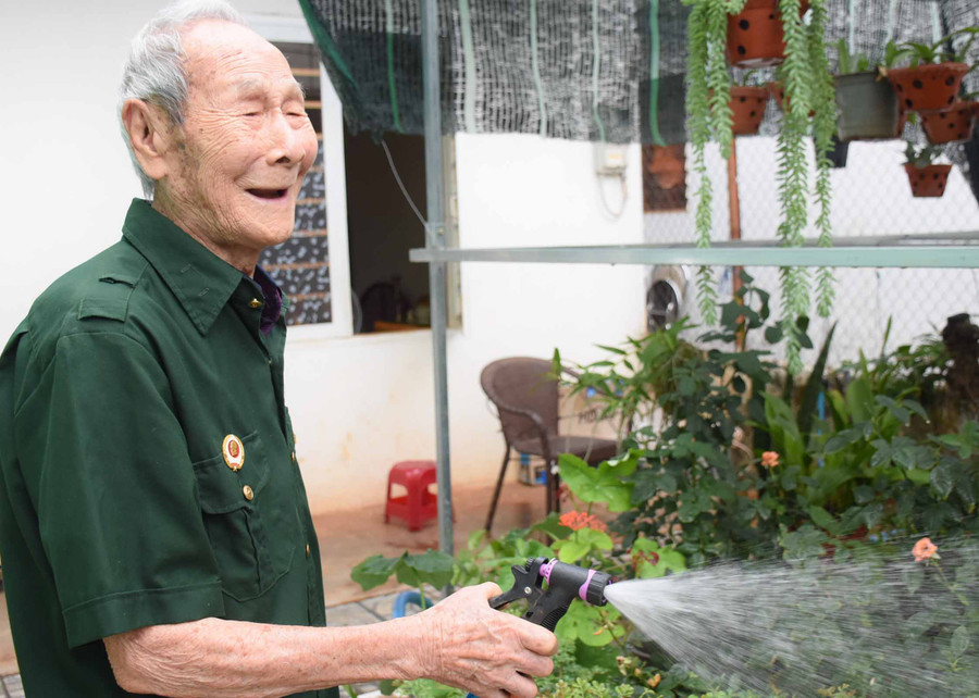 Niềm vui mỗi sáng của ông Trần Đức Tấn là chăm cây, tưới hoa. Ảnh: Phương Duyên
