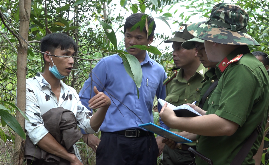 Tạ Văn Huy (bìa trái) được đưa tới để dựng lại hiện trường vụ phá rừng. ẢNH: CACC