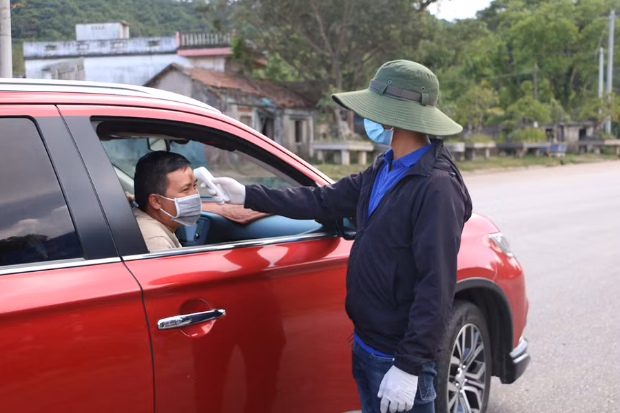 Tiến hành đo thân nhiệt, khai báo y tế đối với tất cả người dân đi vào địa bàn. Ảnh: Quang Tấn