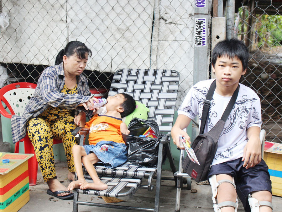 Ba mẹ con Đạt ngồi bán vé số gần miếu Bà Châu Đốc 2. Ảnh: QUANG VIÊN