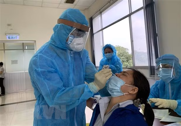 Các y bác sỹ Trung tâm kiểm soát bệnh tật Tp Hồ Chí Minh và Quận 7 thực hiện xét nghiệm sàng lọc COVID-19 ngẫu nhiên cho công nhân ngày 3/6. (Ảnh: Thanh Vũ/TTXVN)