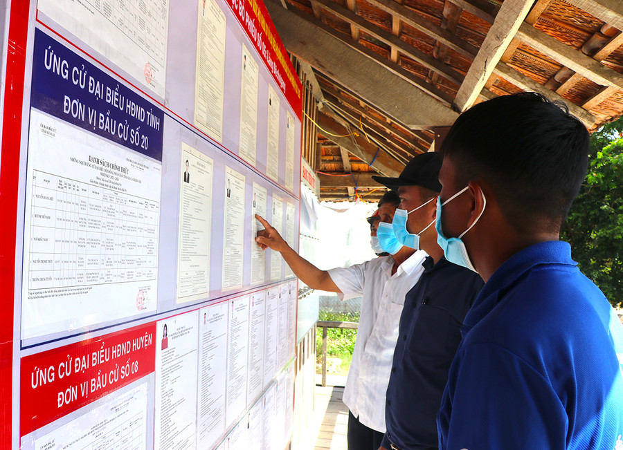  Các cử tri làng Đê Chơ Gang, xã Phú An, huyện Đak Pơ tìm hiểu tiểu sử của các ứng cử viên trước khi đi bỏ phiếu. Ảnh: Ngọc Minh