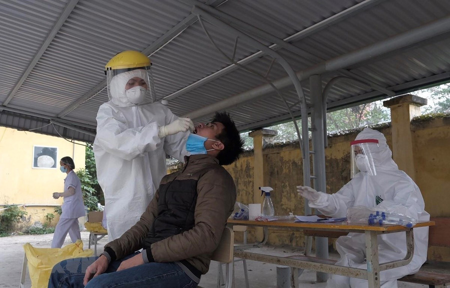 Nhân viên y tế lấy mẫu xét nghiệm COVID-19 với người có tiếp xúc gần với ca F0 tại Hà Nội. (Ảnh: Phạm Hùng - TTXVN phát)