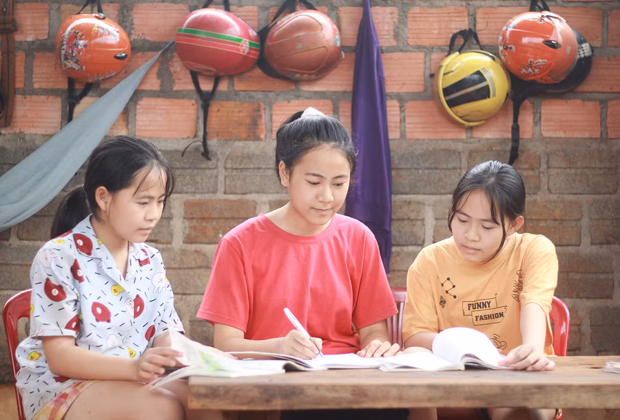 Đoàn Thị Nhị Thảo (ở giữa) hướng dẫn bài cho 2 em gái. Ảnh: Thủy Bình