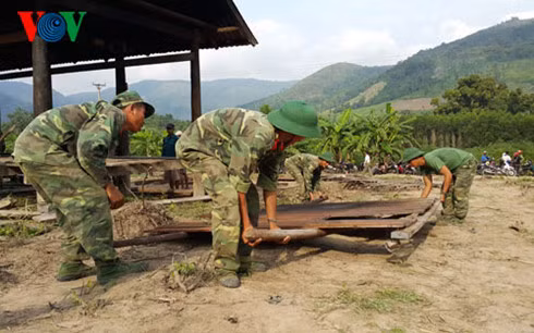 Bộ đội và thanh niên giúp dân dựng nhà tại khu tái định cư.