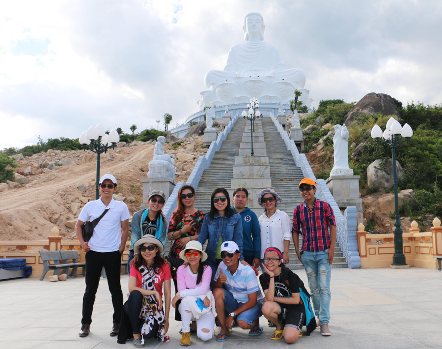 Du khách chụp ảnh lưu niệm dưới chân tượng Phật Thích Ca. Ảnh: Q.T