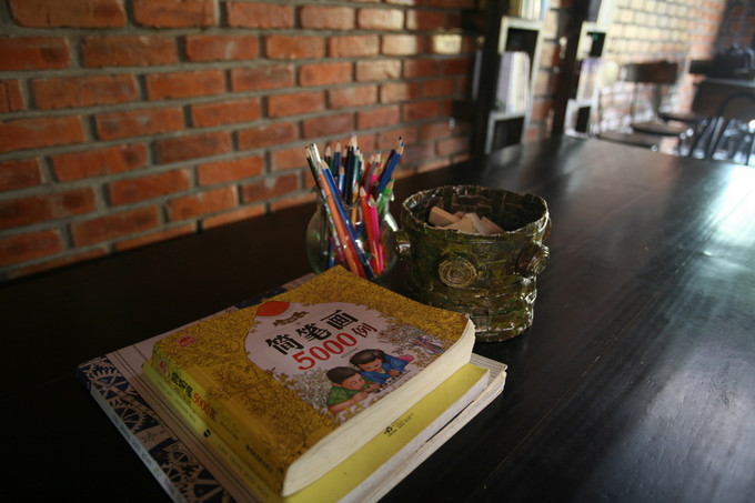 Trên chiếc bàn dài, có những cuốn sách tô màu và ống bút chì dành cho những em bé học tiếng Anh tại nhà cô giáo chơi sau giờ học.