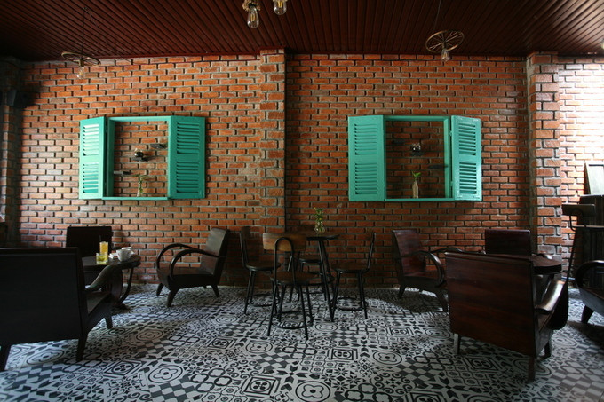  Chủ quán là người thiết kế và giám sát thi công nơi này. Chất liệu và màu sắc chủ đạo được chọn là gạch để mộc không trát, gỗ và nền gạch bông đen trắng. Quầy bar nằm phía sau cùng, trên mái có một ô lấy sáng làm điểm nhấn của quán.