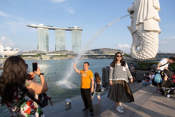 Du khách chụp ảnh trước bức tượng sư tử biển biểu tượng của Singapore. Ảnh: New York Times.