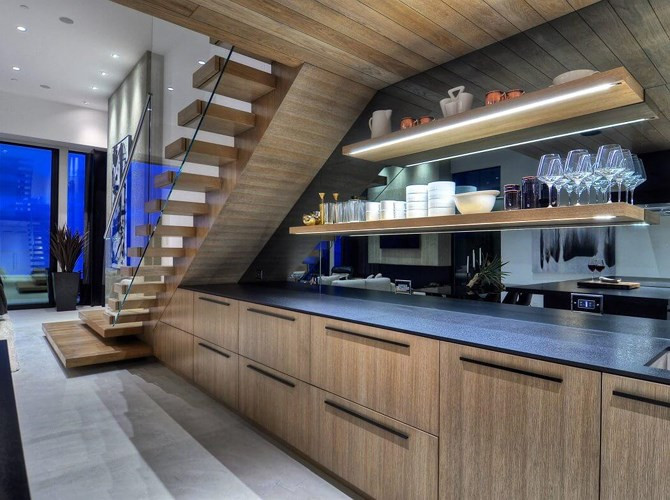  Tủ bếp bằng gỗ đặt dưới cầu thang được nhấn nhá bằng các loại đèn trang trí.