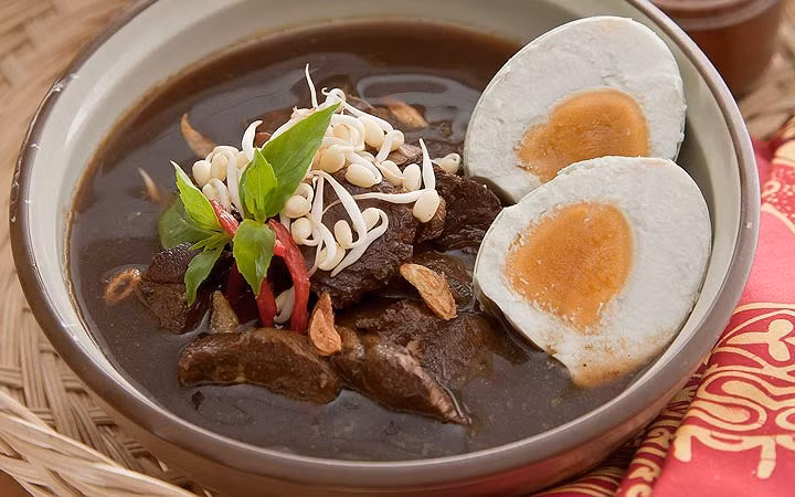 Nasi rawon: Món ăn đặc biệt này được làm từ gạo nấu cùng với nước súp thịt bò đen. Màu đen của nước súp xuất phát từ loại hạt đen keluak. Ảnh Youtube