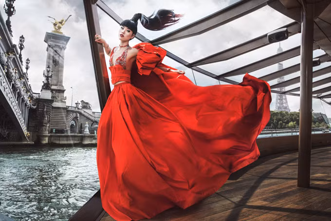 Trước khi tổ chức show diễn trên thuyền ở Paris, Jessica Minh Anh thực hiện bộ ảnh thời trang ấn tượng. Cô mặc váy dạ hội đỏ rực, tạo dáng trên con tàu đang chạy quanh sông Seine.