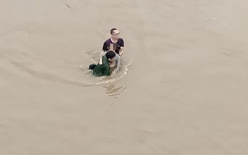 Anh Chung và anh Hoàng mỗi người một bên dìu cô gái lên bờ (Ảnh: Dân Việt).