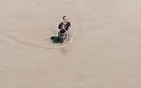 Anh Chung và anh Hoàng mỗi người một bên dìu cô gái lên bờ (Ảnh: Dân Việt).