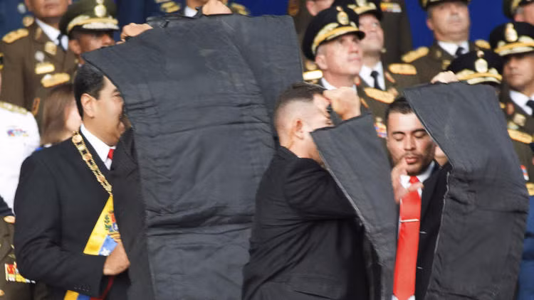 Vệ sĩ che chắn cho Tổng thống Venezuela khi ông bị UAV tấn công. Ảnh: Xinhua