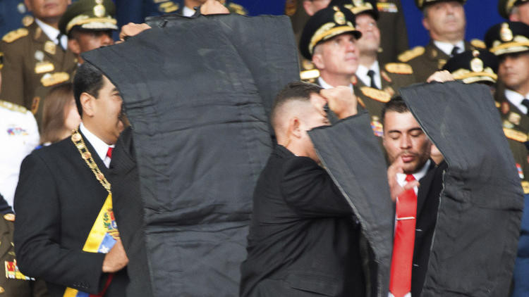 Vệ sĩ che chắn cho Tổng thống Venezuela khi ông bị UAV tấn công. Ảnh: Xinhua