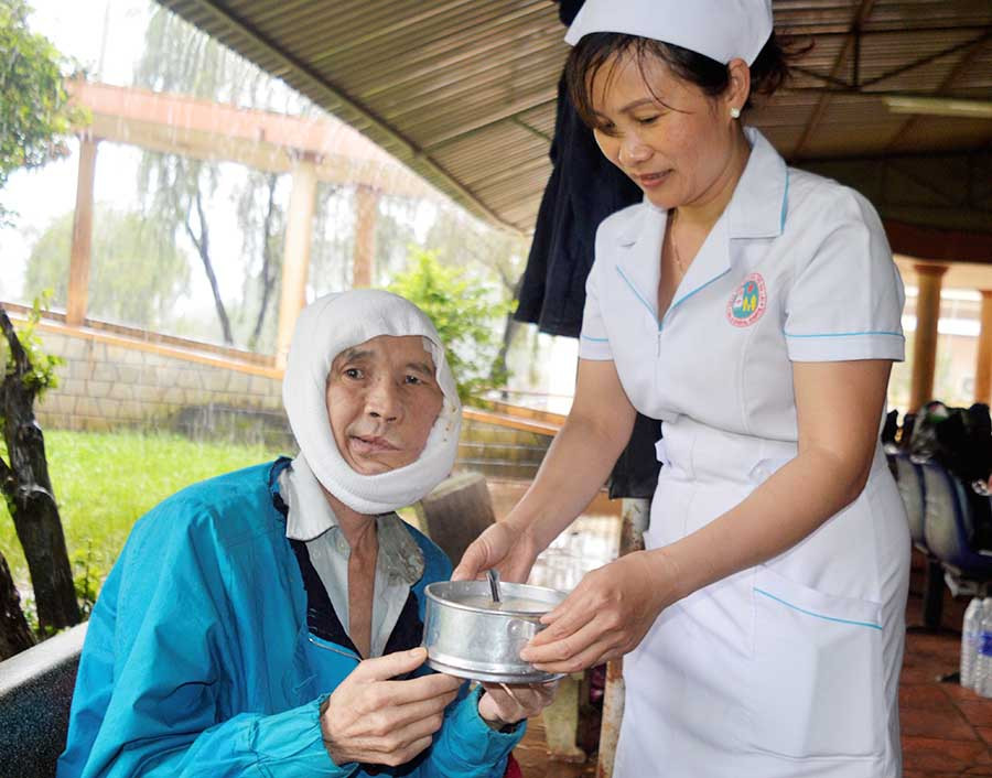  Ông Tấn được chị Phương giúp đỡ lấy những bát cháo từ thiện ở bệnh viện. Ảnh: Đ.Y