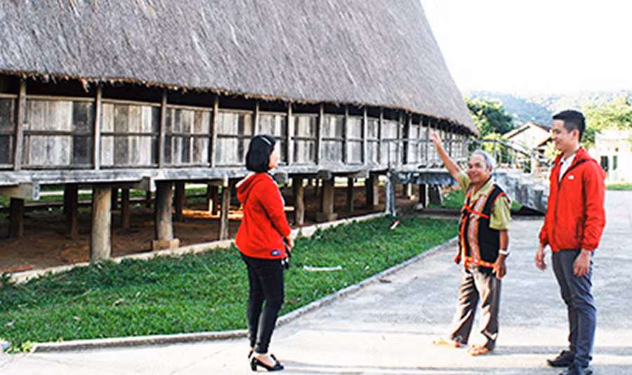 Già làng A Jring Đeng giới thiệu nhà rông của làng với du khách. Ảnh: H.T