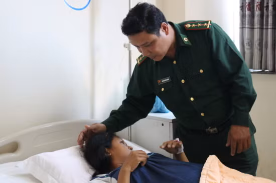 Thượng úy Nguyễn Doãn Quân thăm khám vết va đập trên đầu chị Chương Sro. Ảnh: Bích Nguyên
