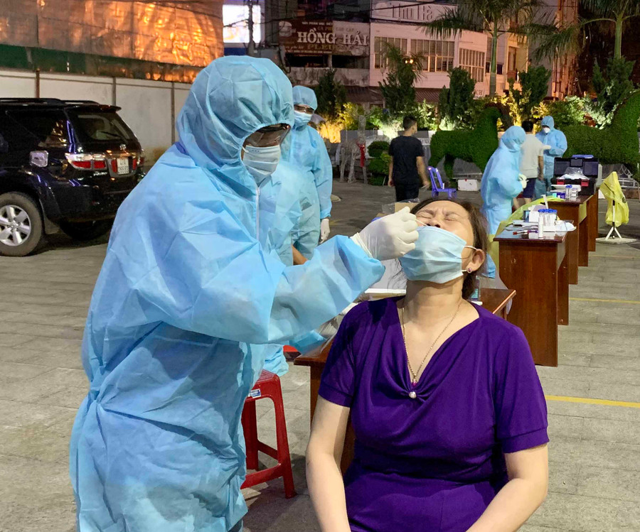 Nhân viên y tế lấy mẫu xét nghiệm sàng lọc SARS-CoV-2 tại chợ đêm Pleiku. Ảnh: Như Nguyện