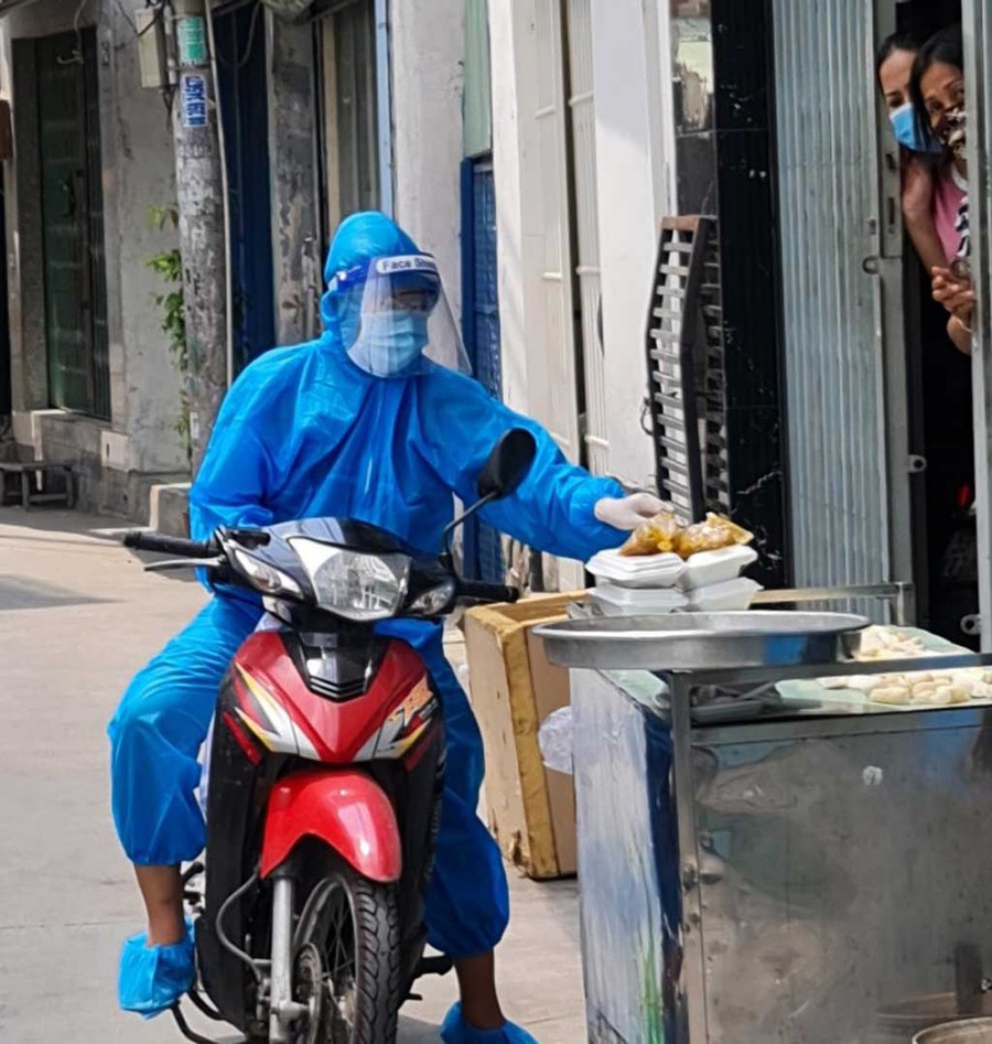 Tình nguyện viên lái xe máy đi phát cơm cho người dân. ẢNH: NAM NGUYỄN