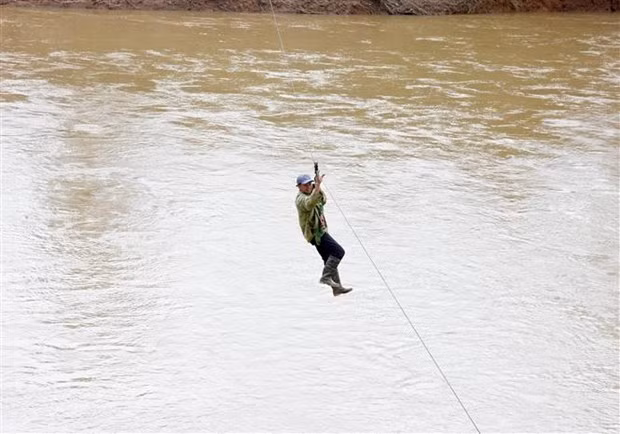 Người dân liều mình đu dây qua sông Pô Kô. (Ảnh: Khoa Chương/TTXVN)