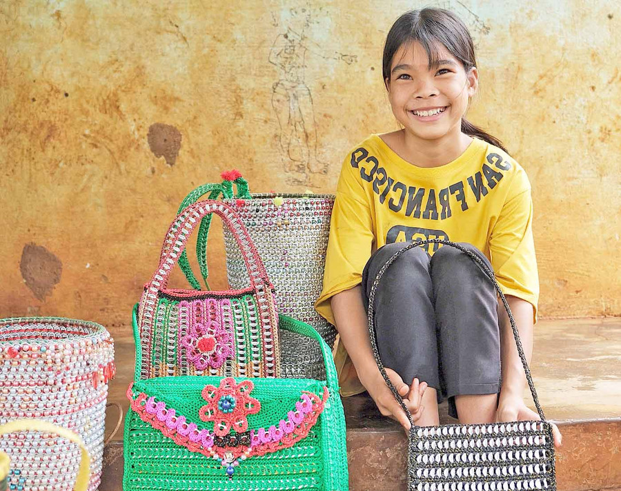 Em Rơ Mah San (làng Dơk Lah, xã Ia Dơk, huyện Đức Cơ) bên các sản phẩm thủ công được làm từ vật liệu tái chế. Ảnh: Minh Châu